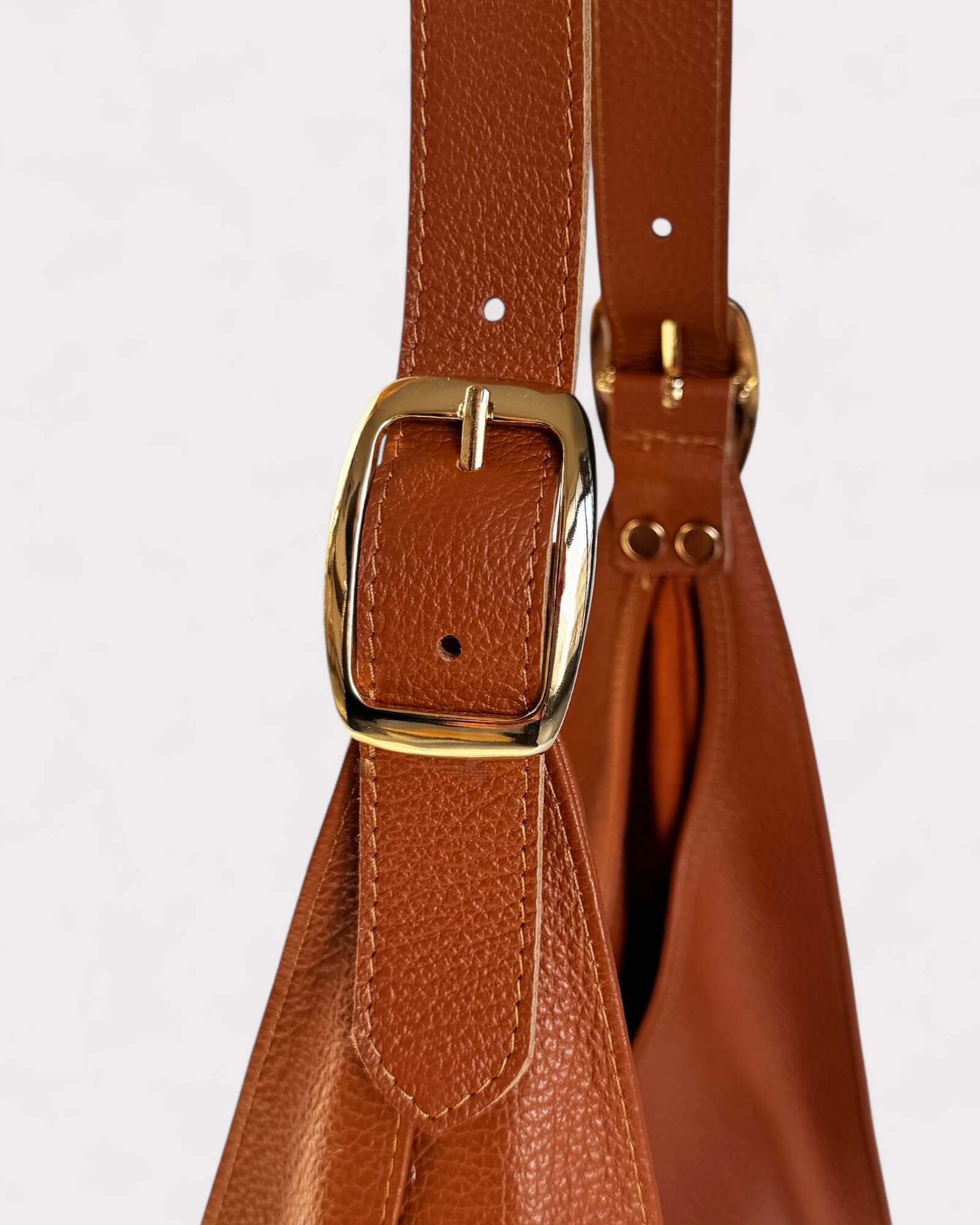 Tan leather bag with gold buckle on a light gray background