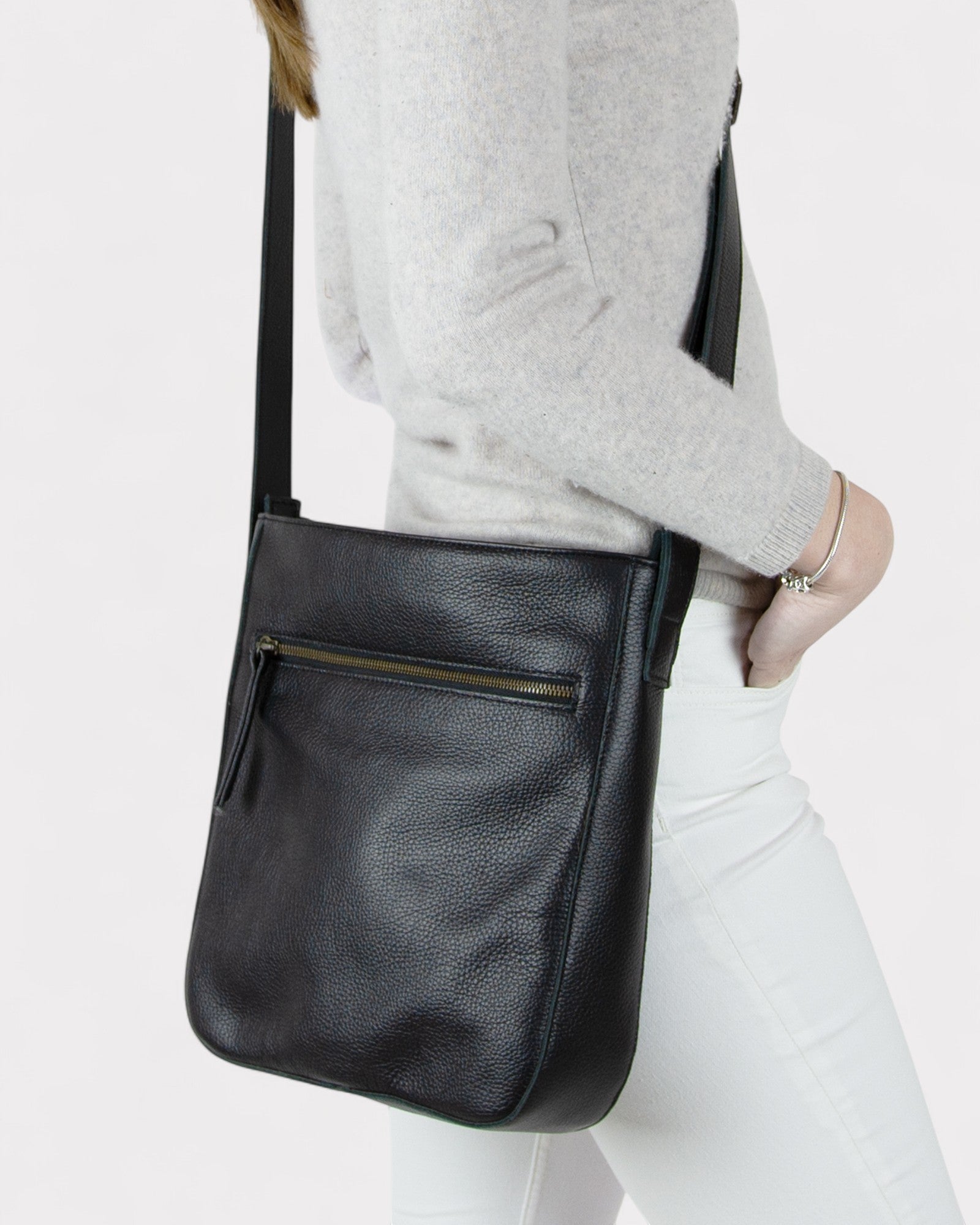 Person wearing a black leather crossbody bag on a white background