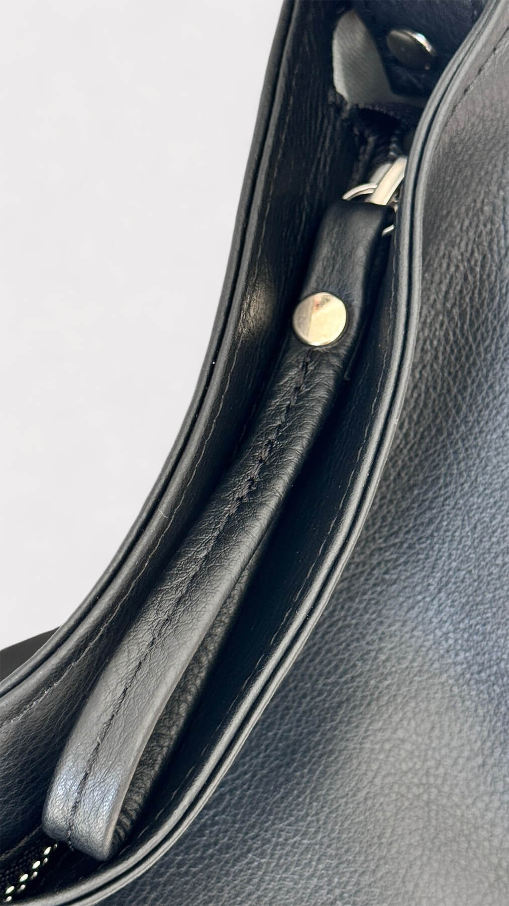 Close-up of a black leather bag zipper pull