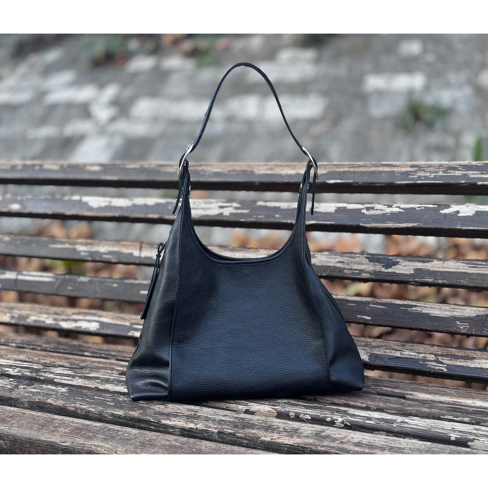 Black handbag on a wooden bench with a blurred background