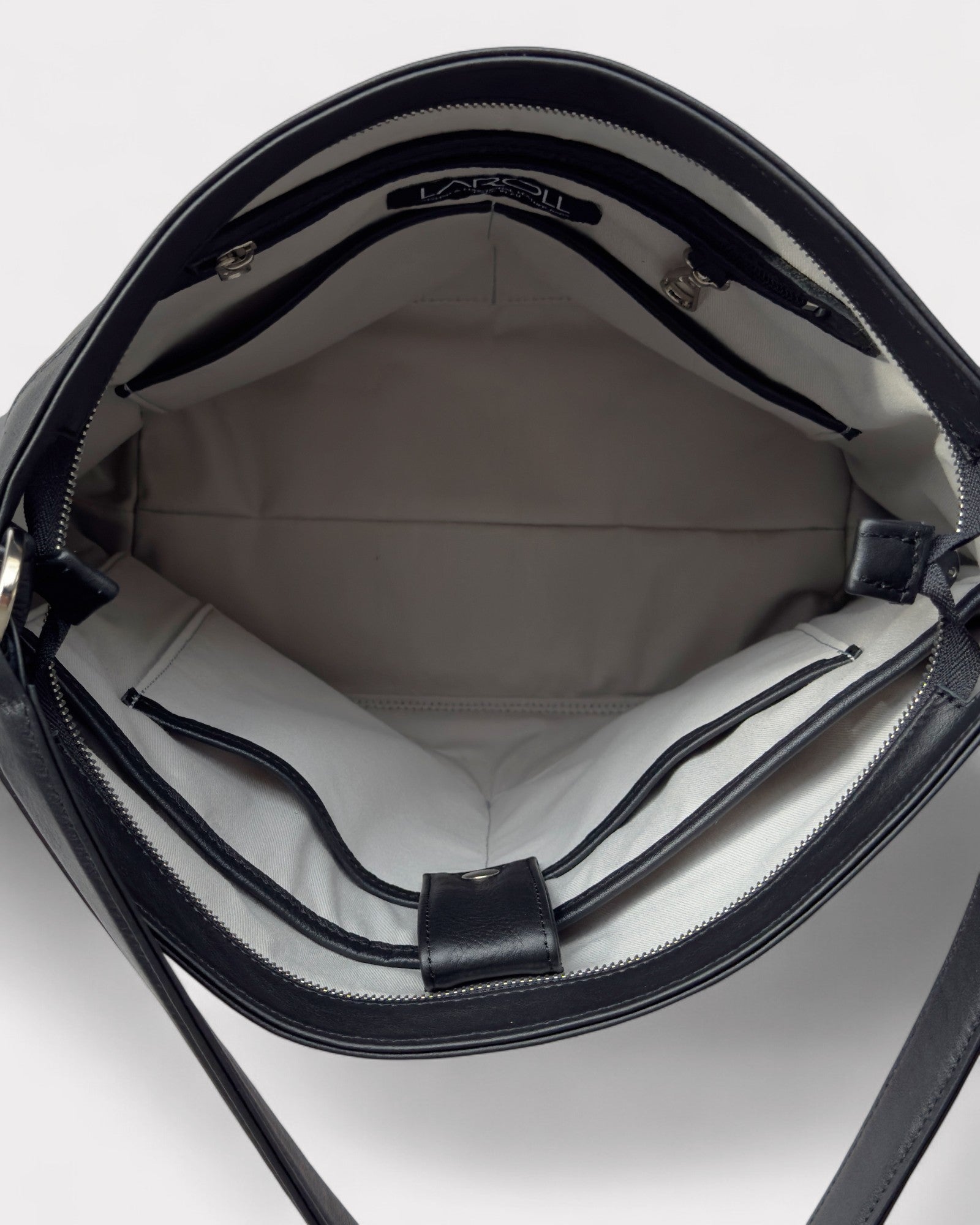 Close-up of a black handbag with visible brand name on a white background