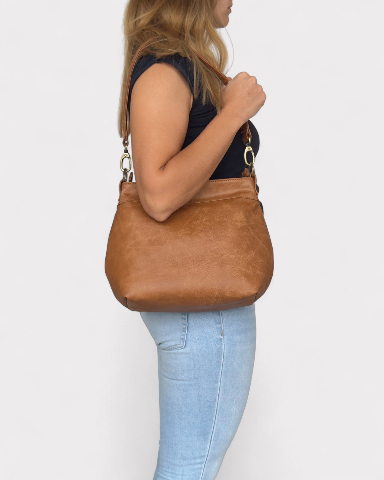 Person holding a tan distressed  handbag against a white background