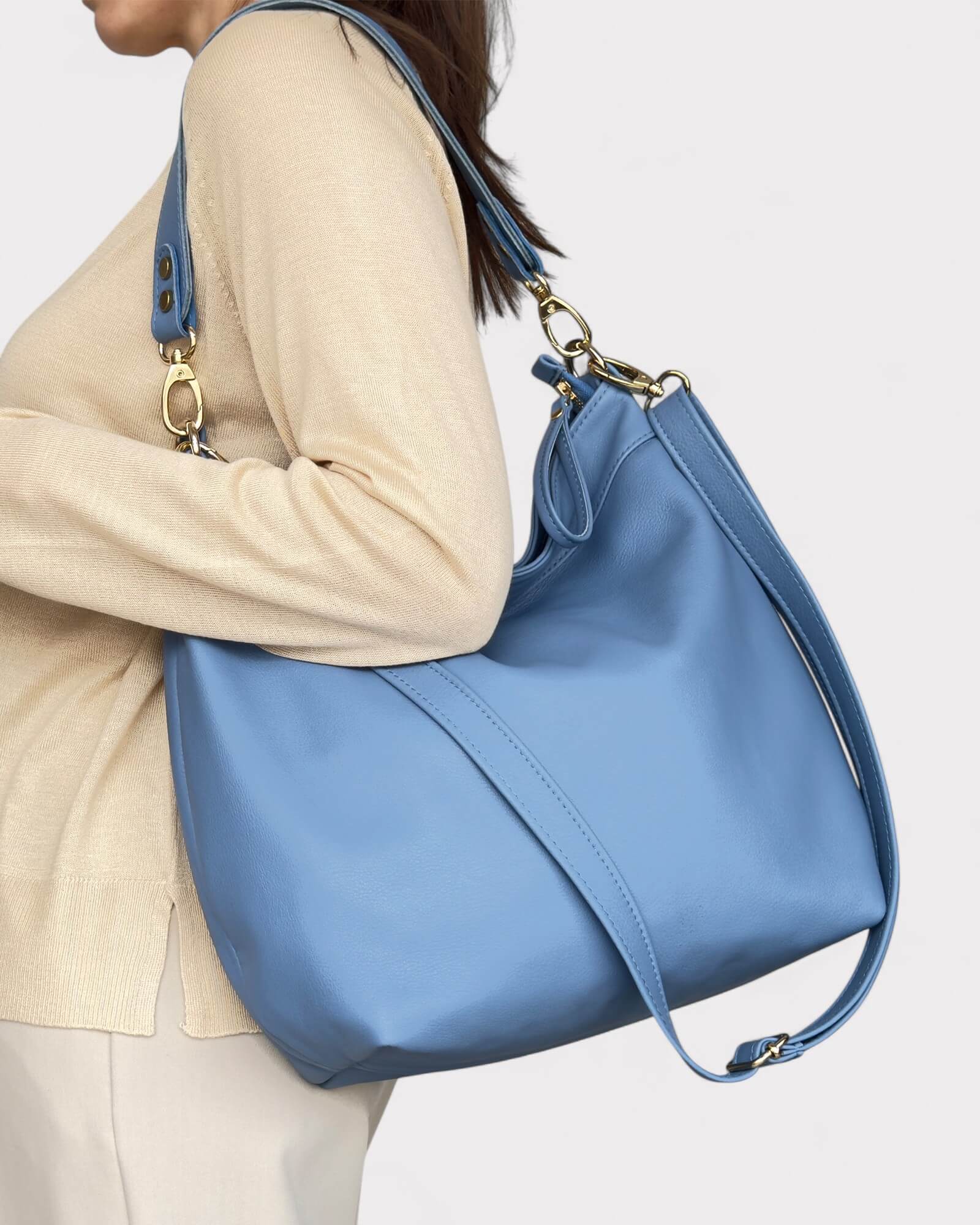 Blue handbag carried by a person on a light background