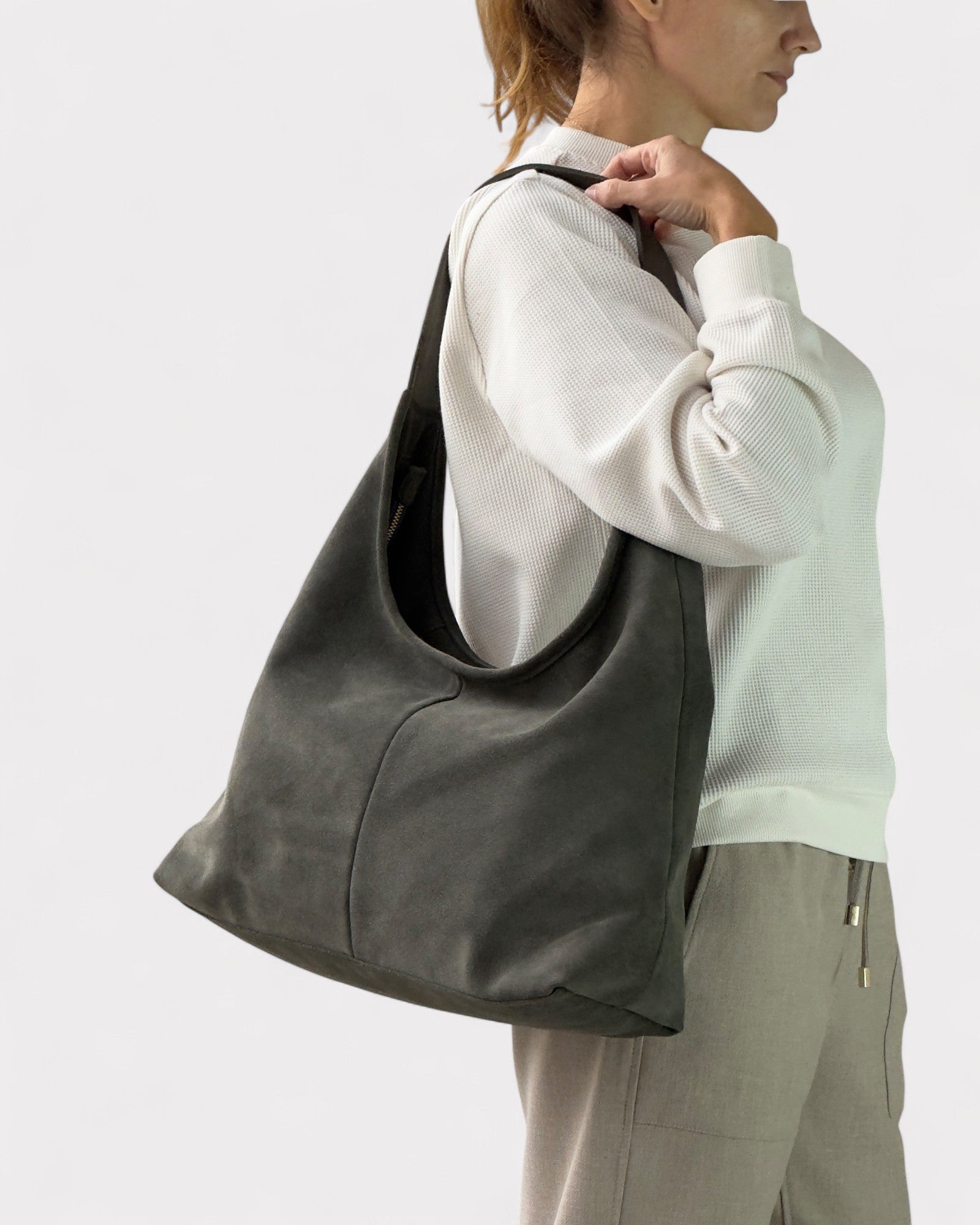 Person holding a large green leather bag against a white background