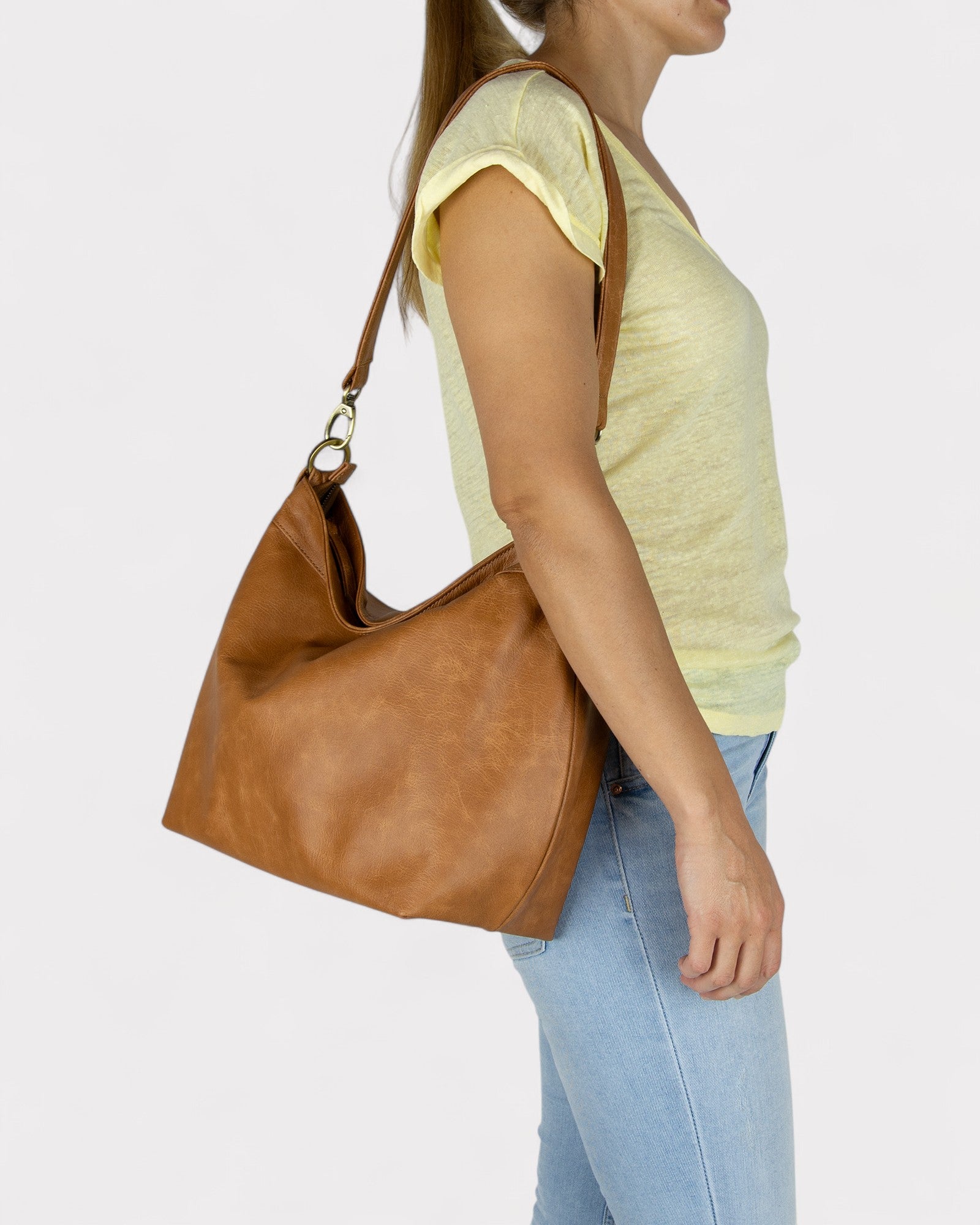Woman carrying a Tan distressed leather handbag on a white background