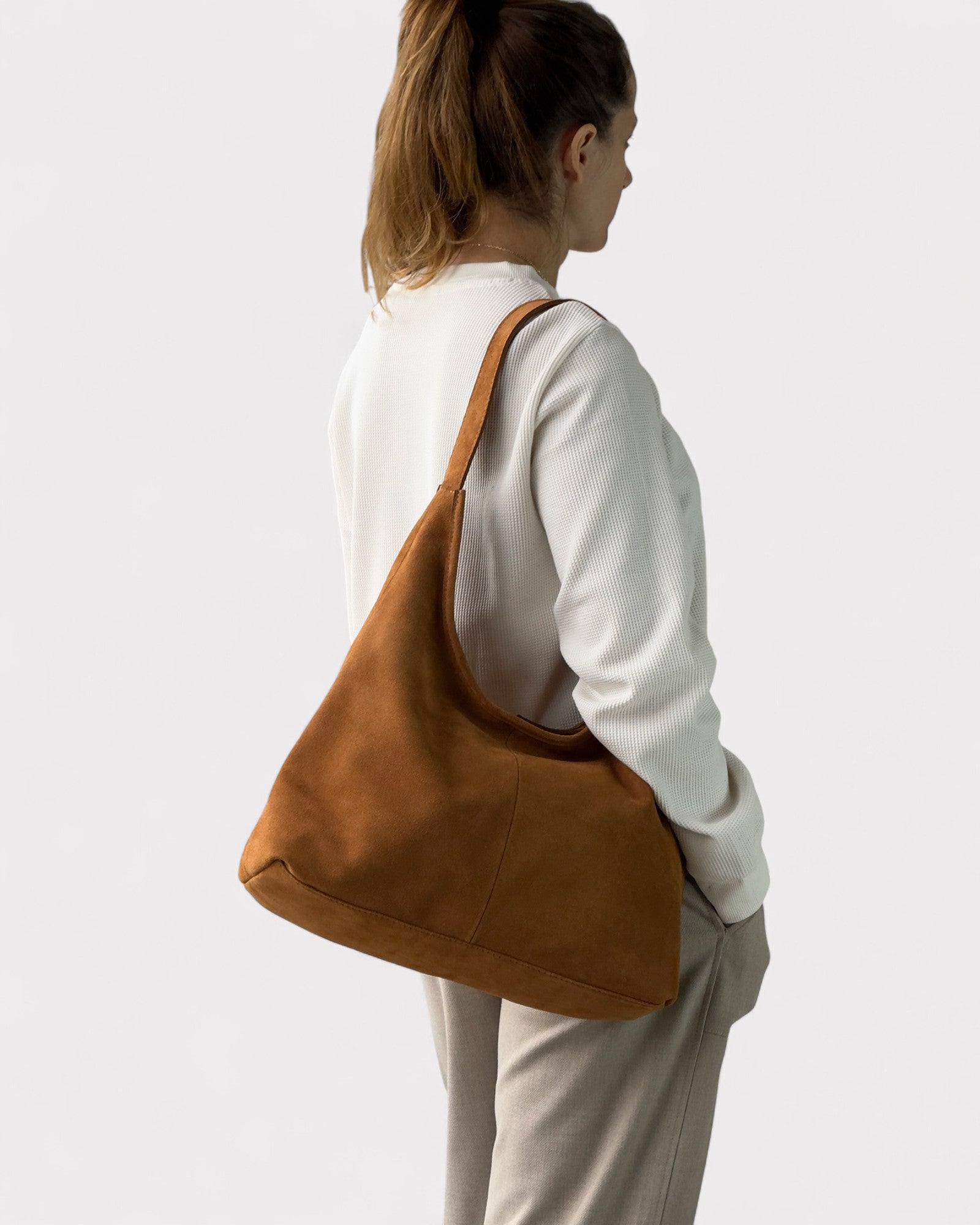 Person wearing a tan shoulder bag on a plain background