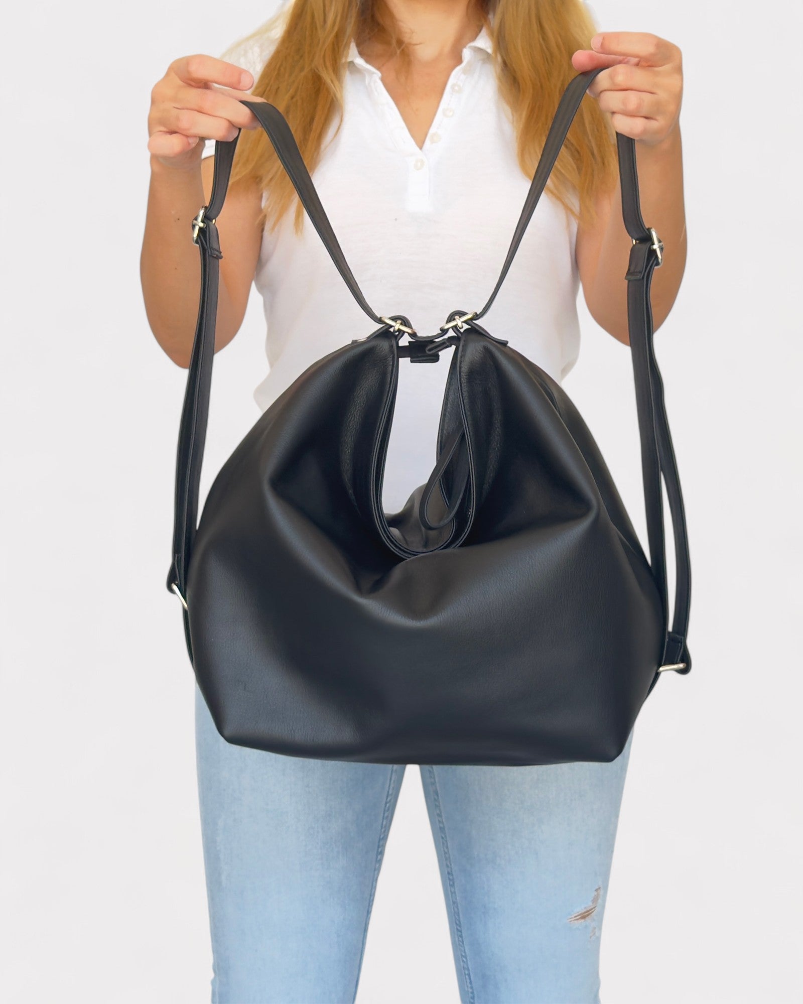 Person holding a black handbag against a white background