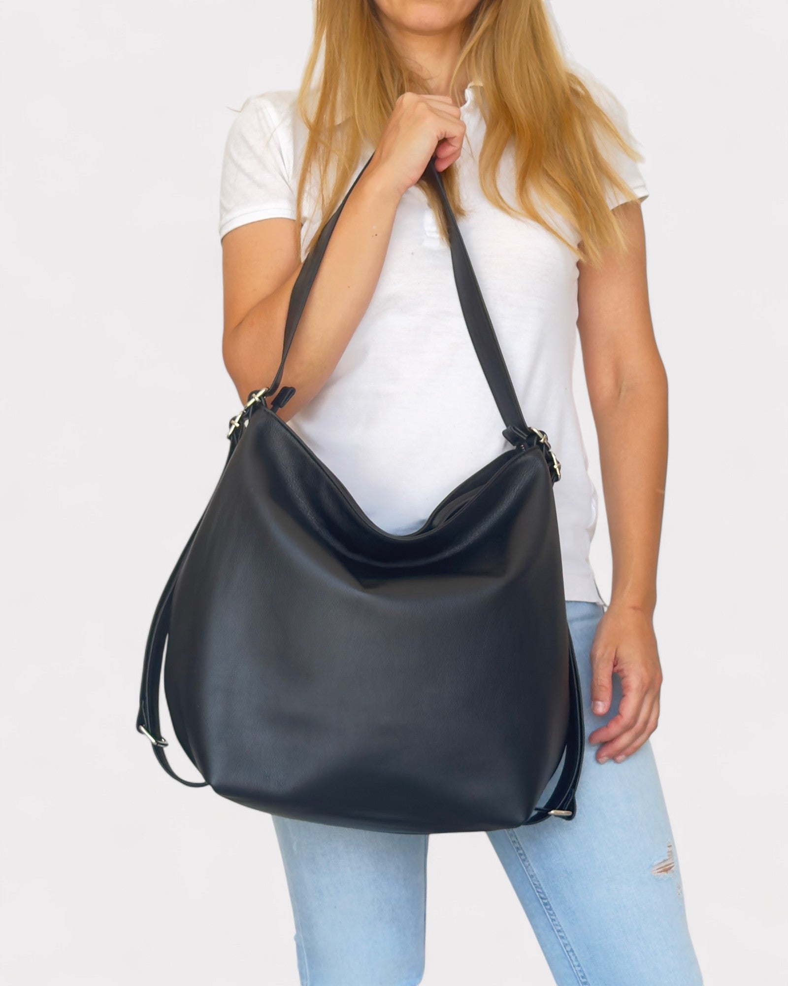 Person holding a black shoulder bag against a white background