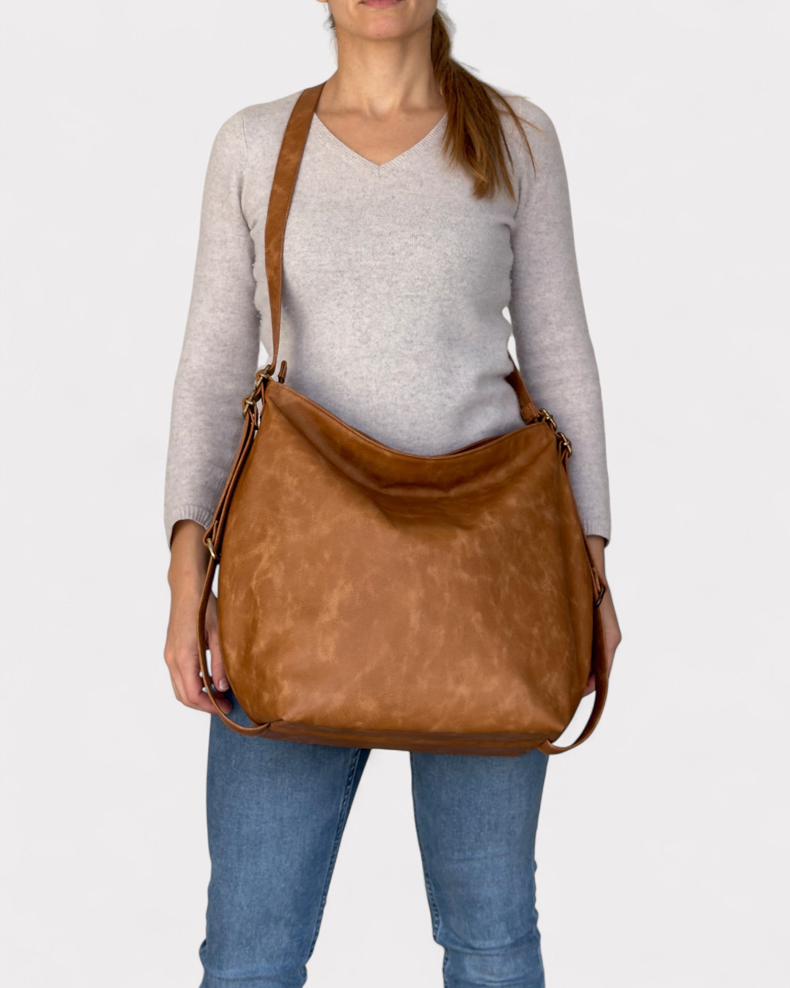 Person holding a tan leather bag against a white background
