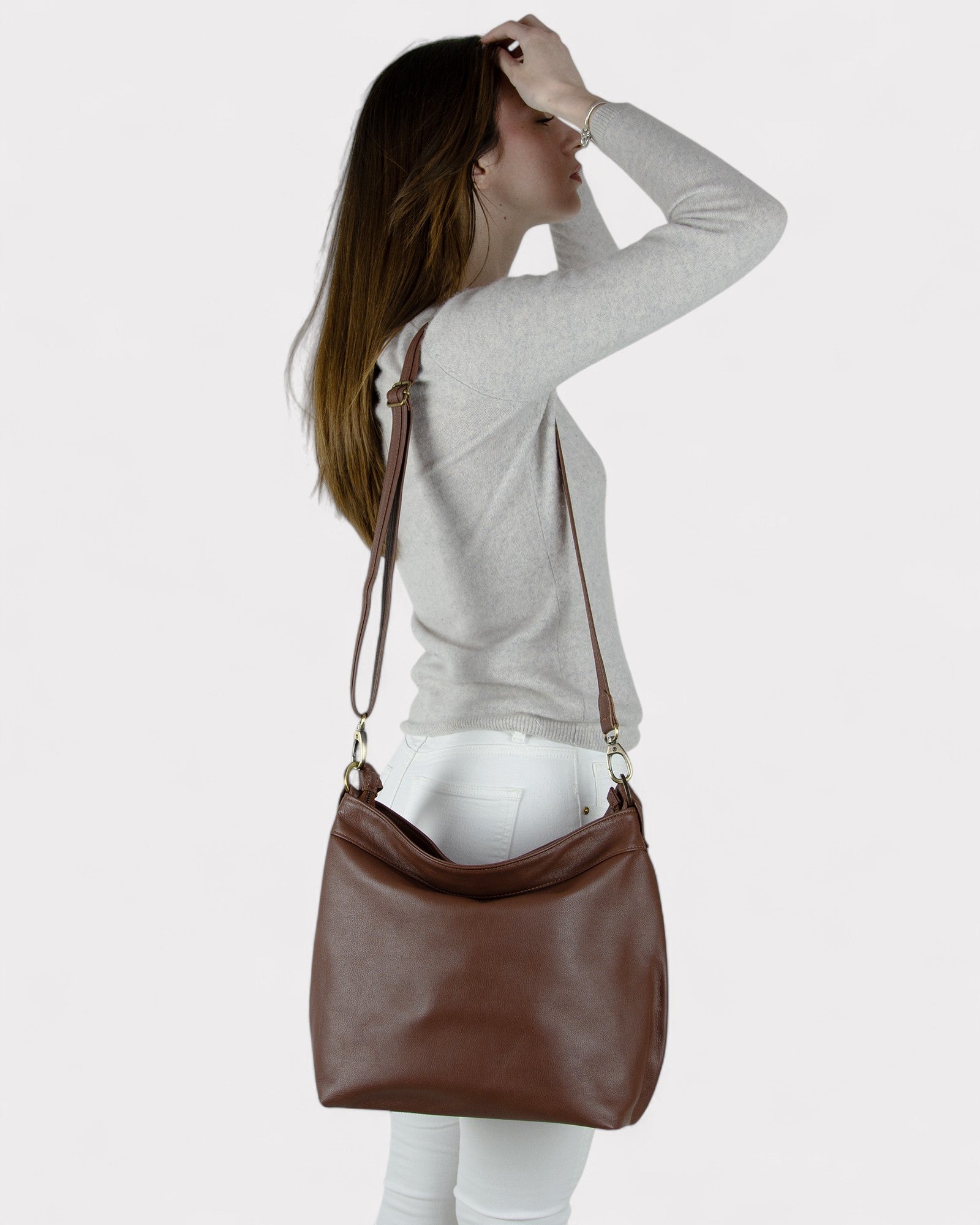Woman carrying a brown leather bag on a plain background