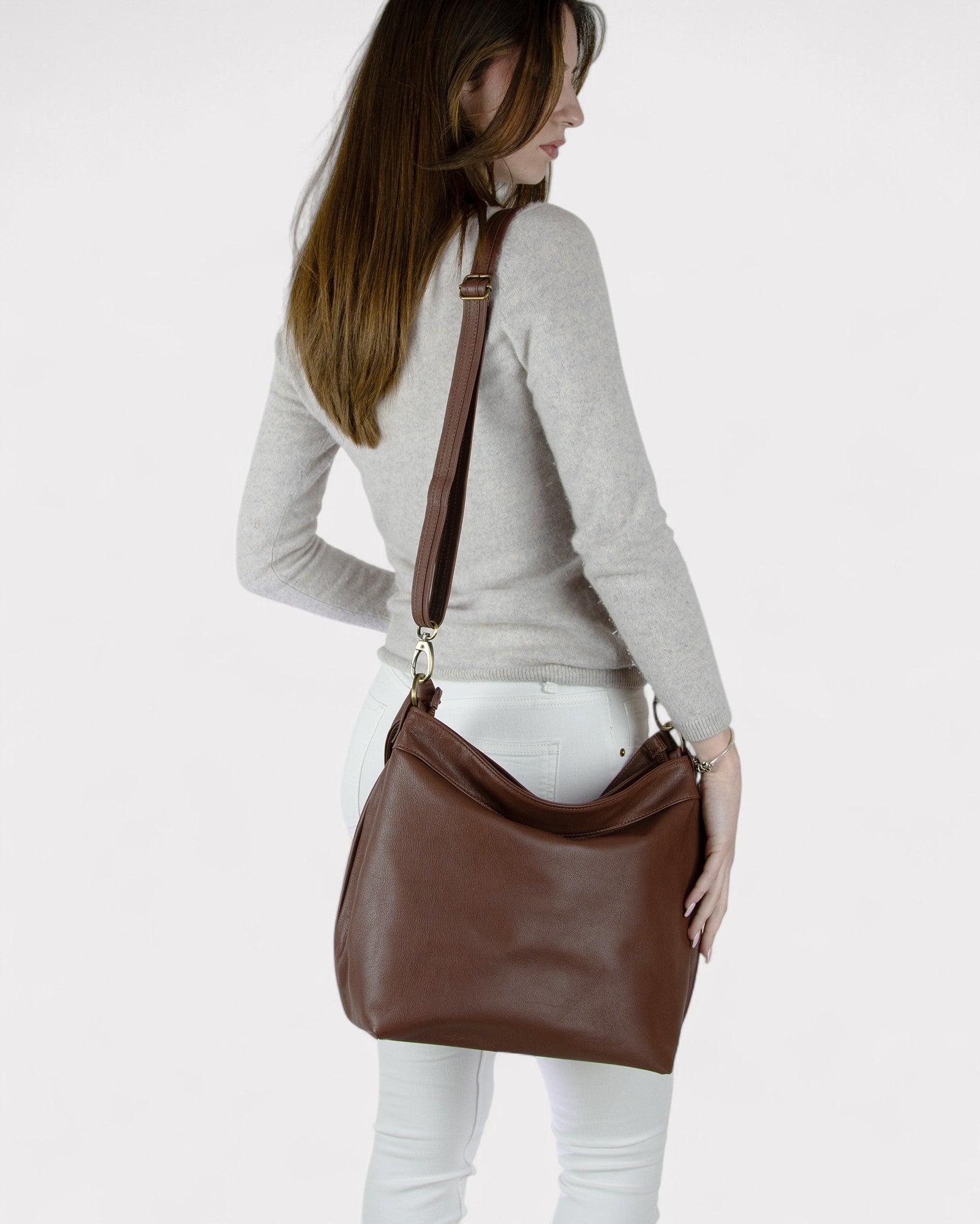 Woman carrying a brown leather handbag on a white background