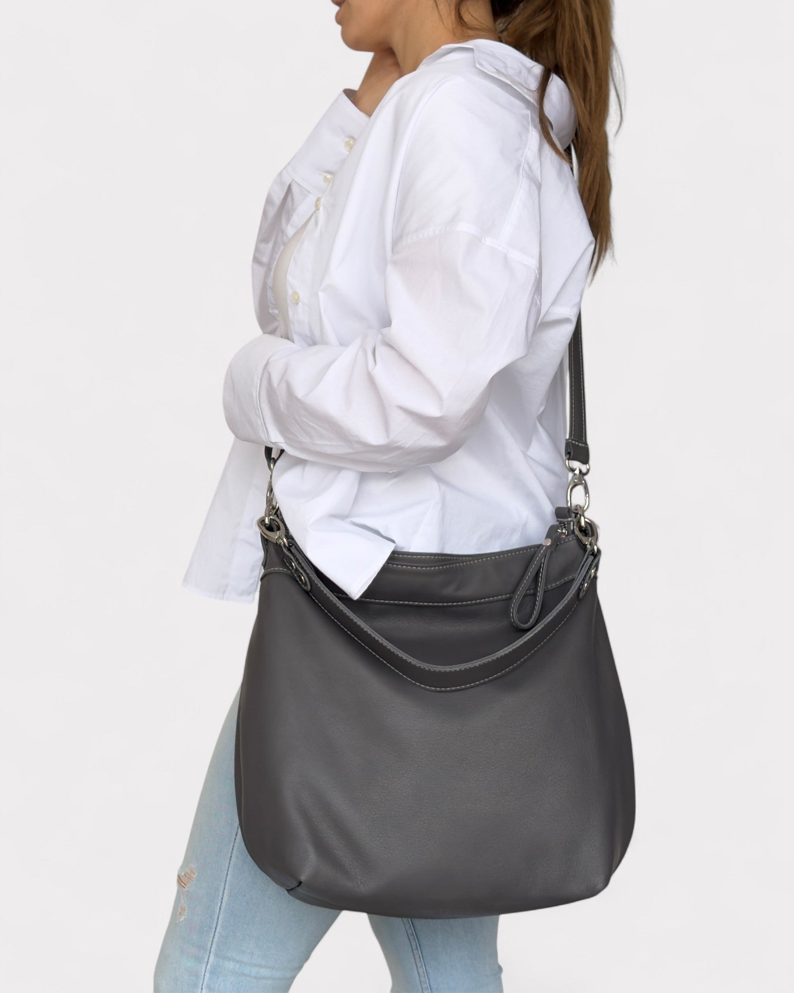 Person wearing a gray shoulder bag on a plain background