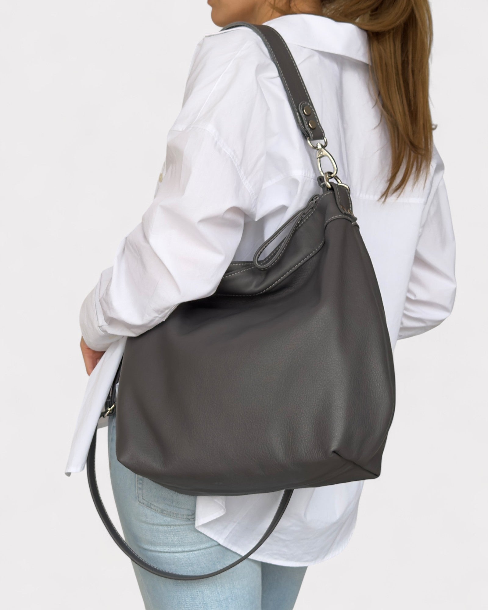 Person wearing a gray shoulder bag on a plain background