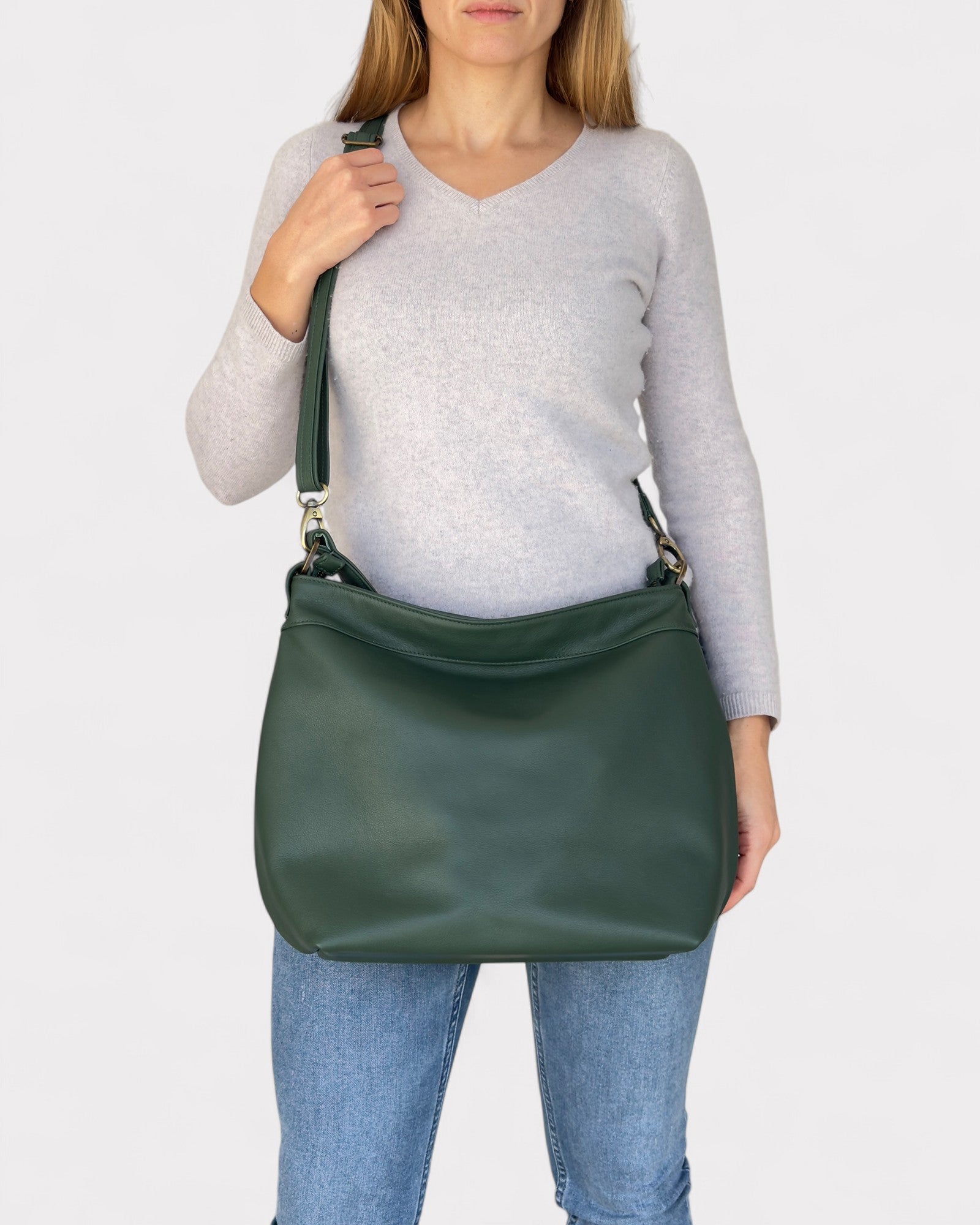 Person wearing a green shoulder bag on a plain background