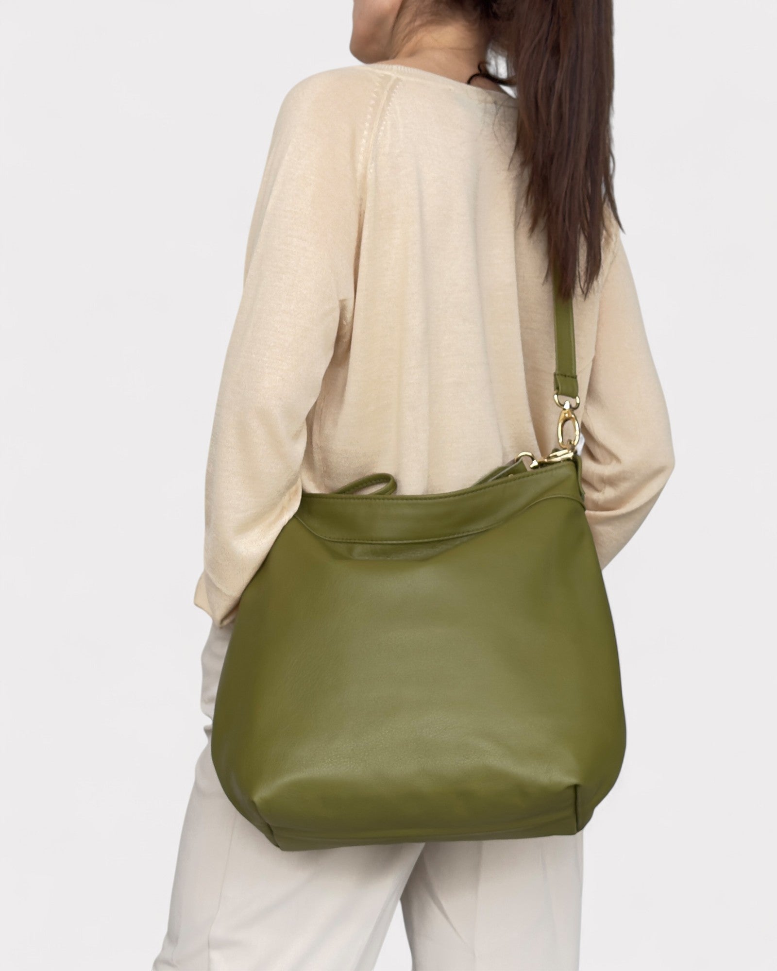 Person wearing a green shoulder bag on a plain background
