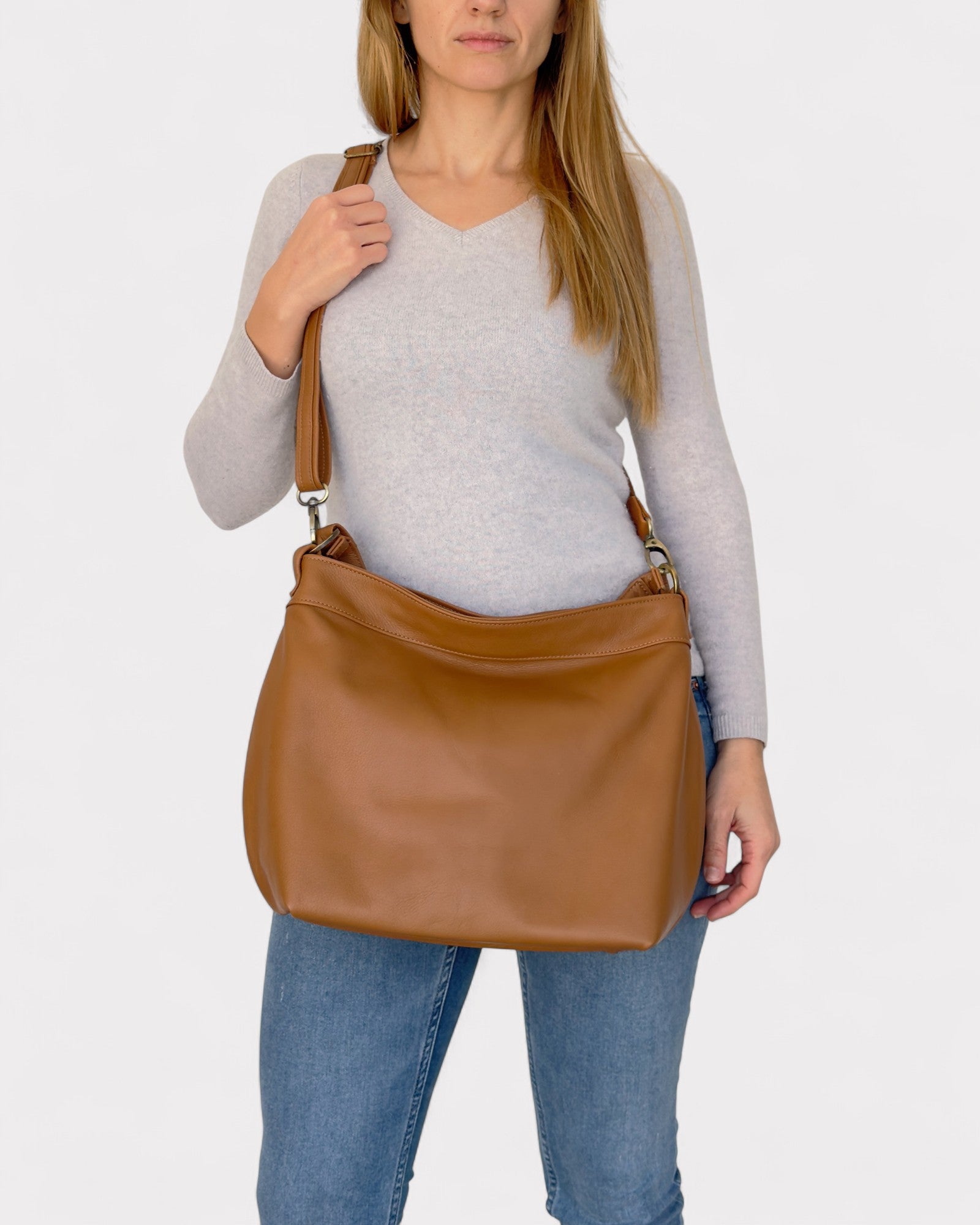 Woman holding a tan leather handbag against a white background