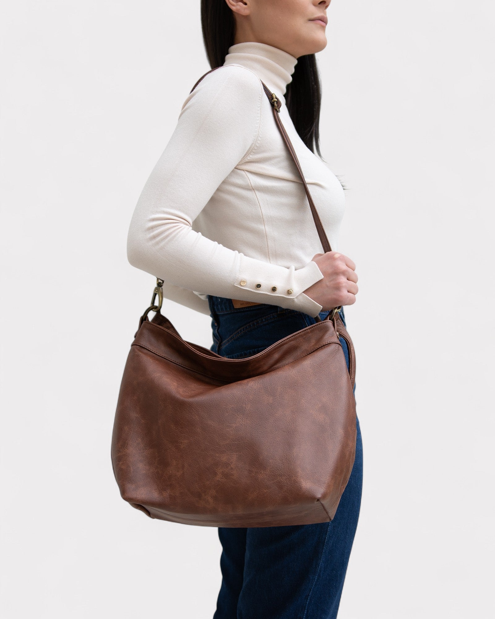 Woman carrying a brown leather handbag on a white background