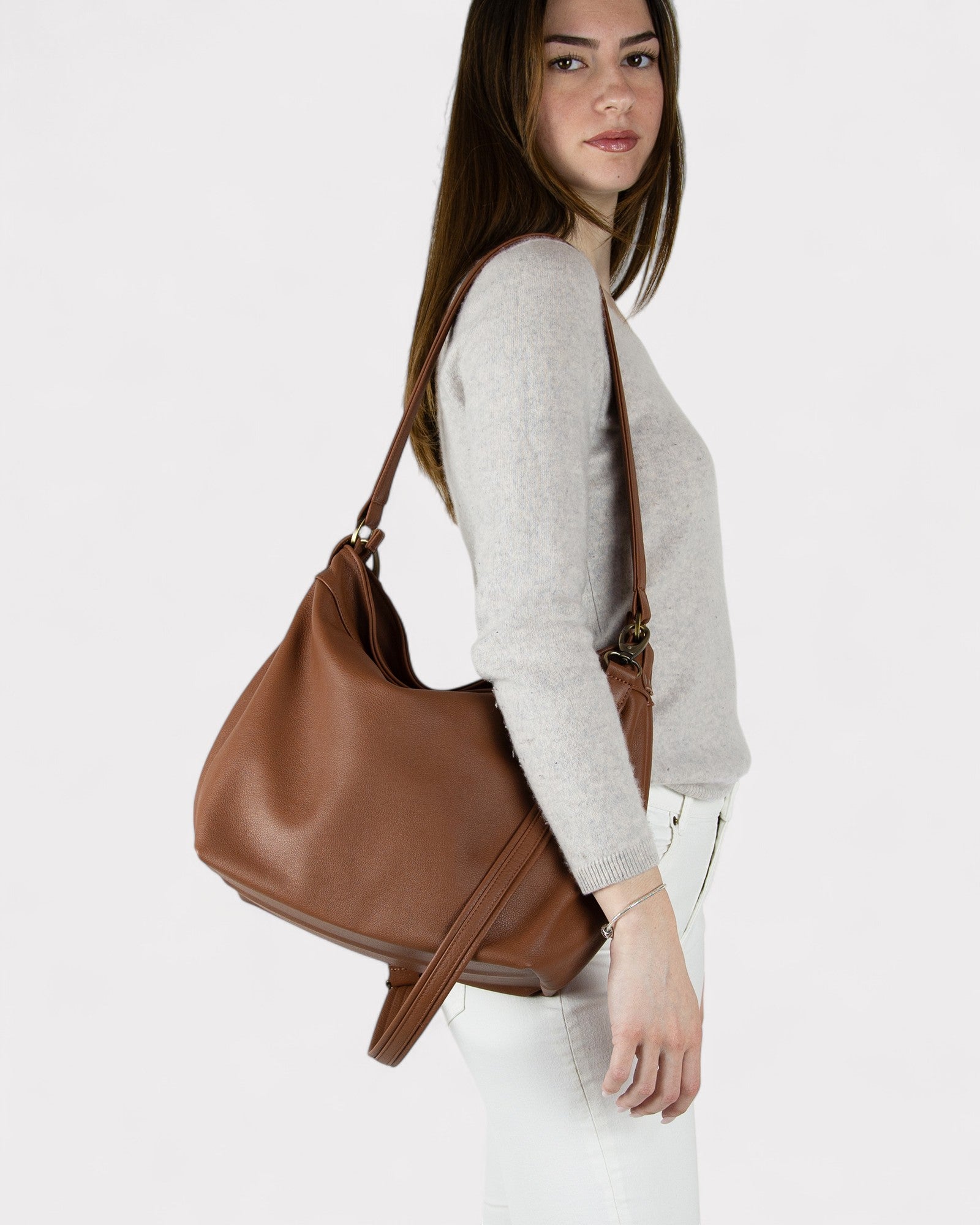 Woman carrying a Cognac brown leather handbag on a white background
