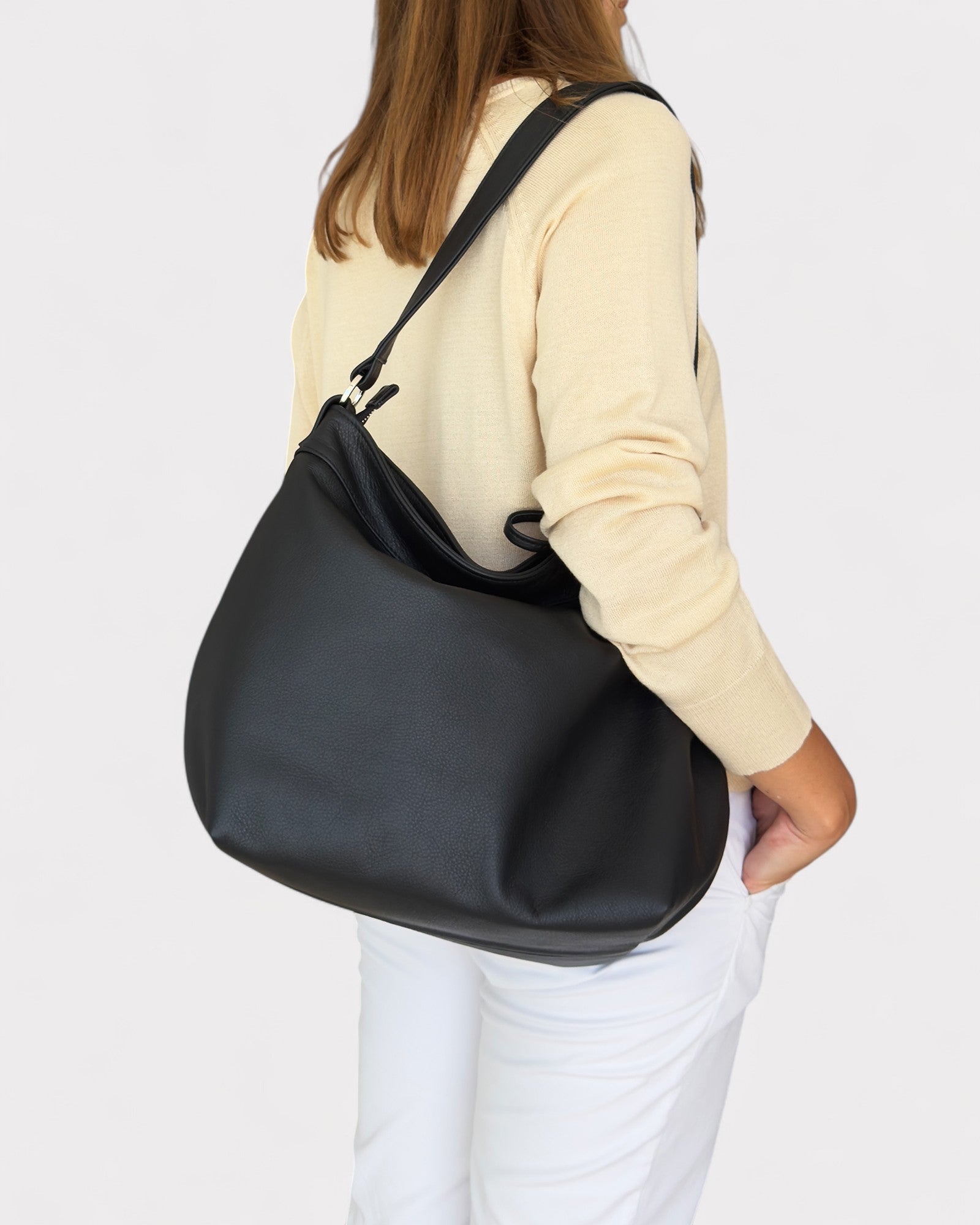 Person wearing a black shoulder bag on a white background