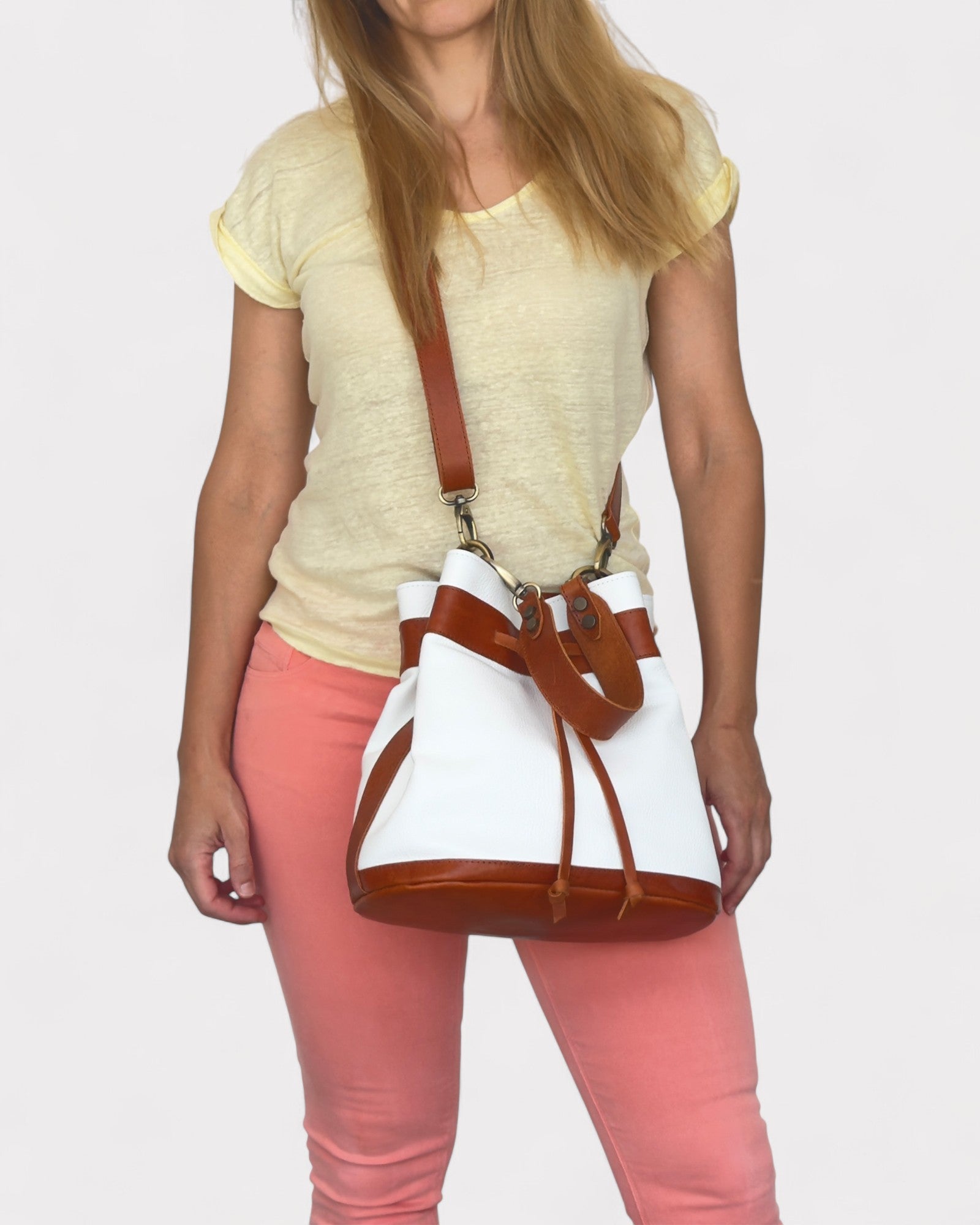 Person holding a white and brown handbag against a plain background