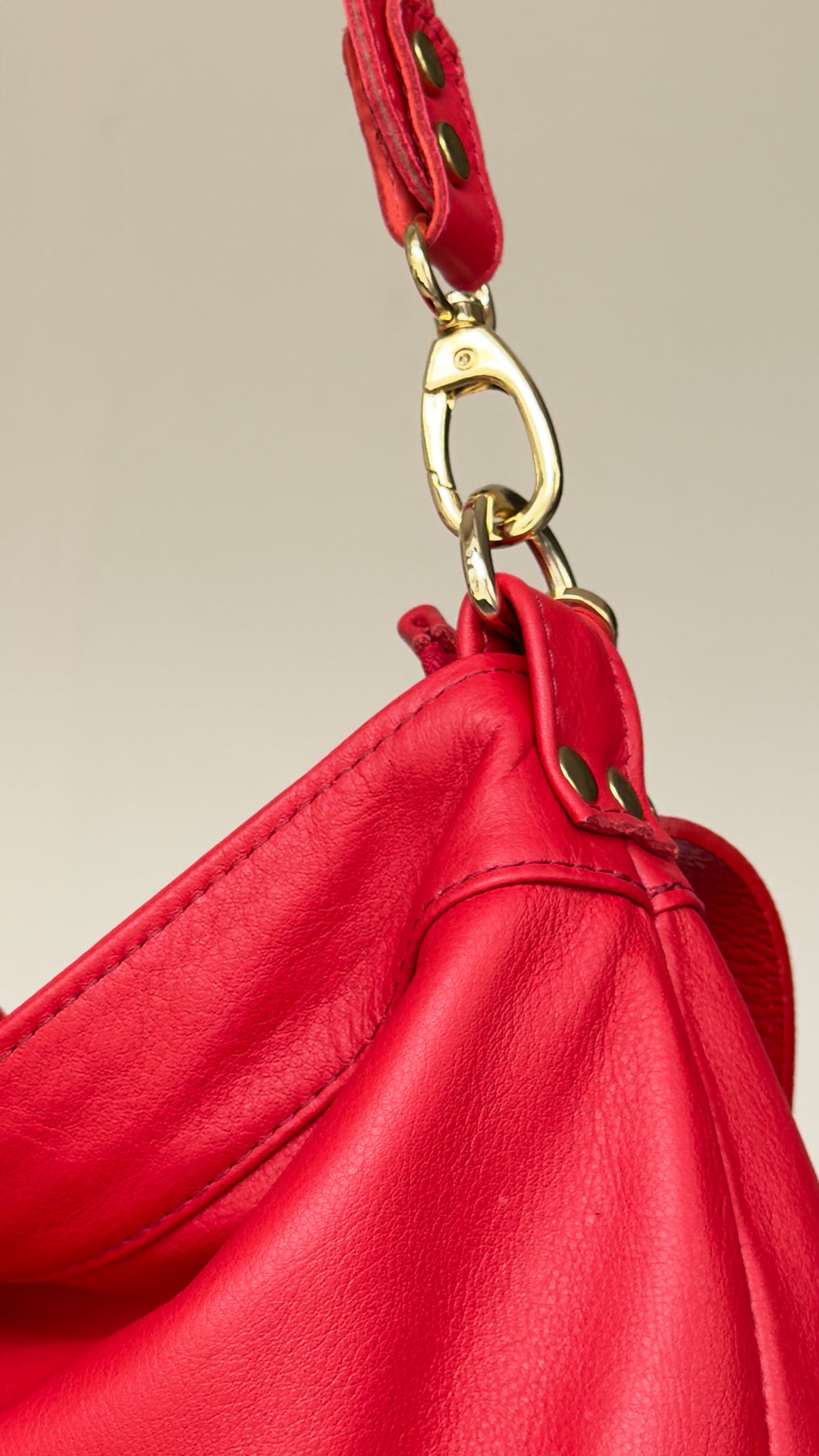 Close-up of a red handbag with a gold clasp on a beige background