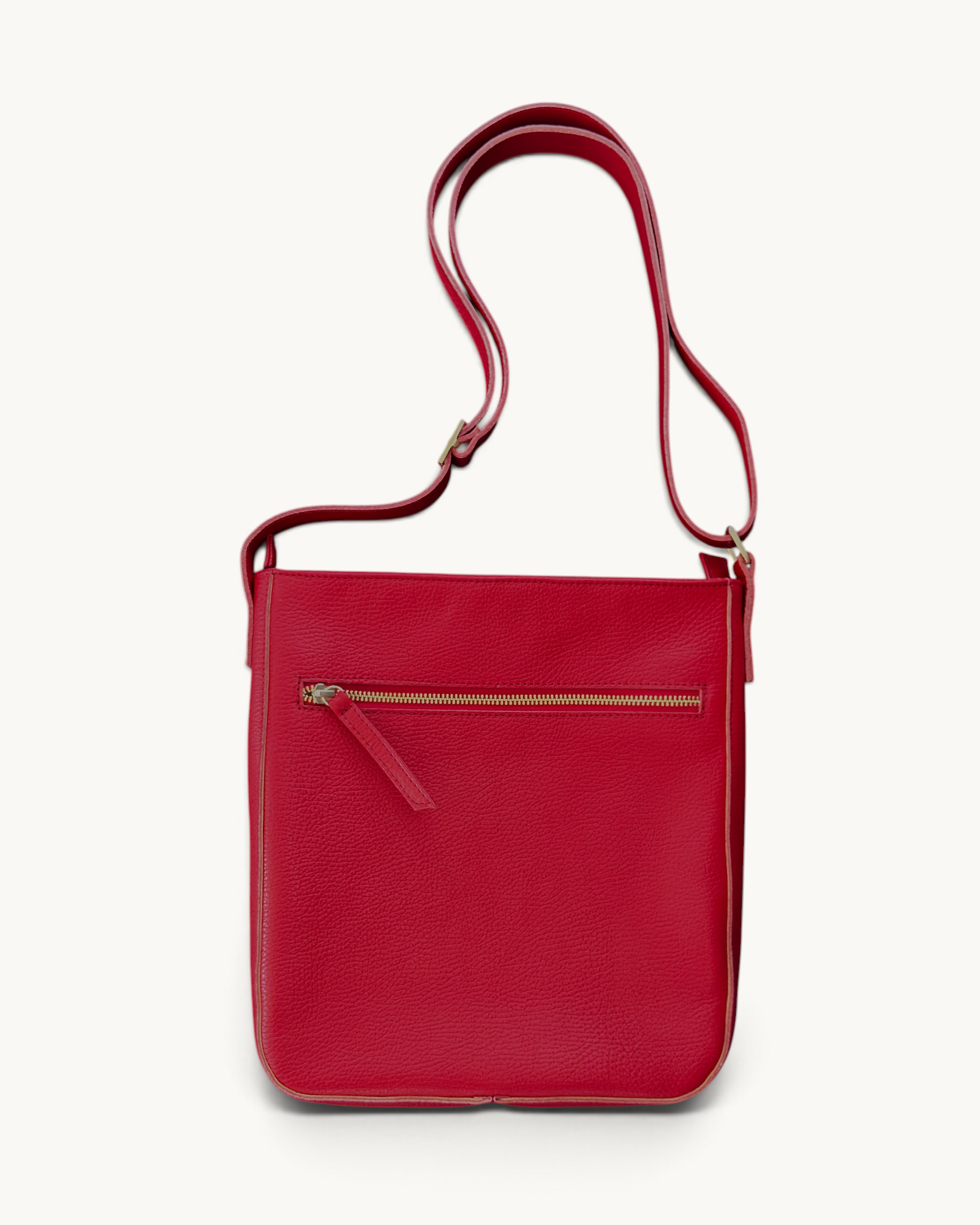 A red pebbled leather crossbody bag with a front zippered pocket and a matching adjustable shoulder strap, shown against a plain off-white background.