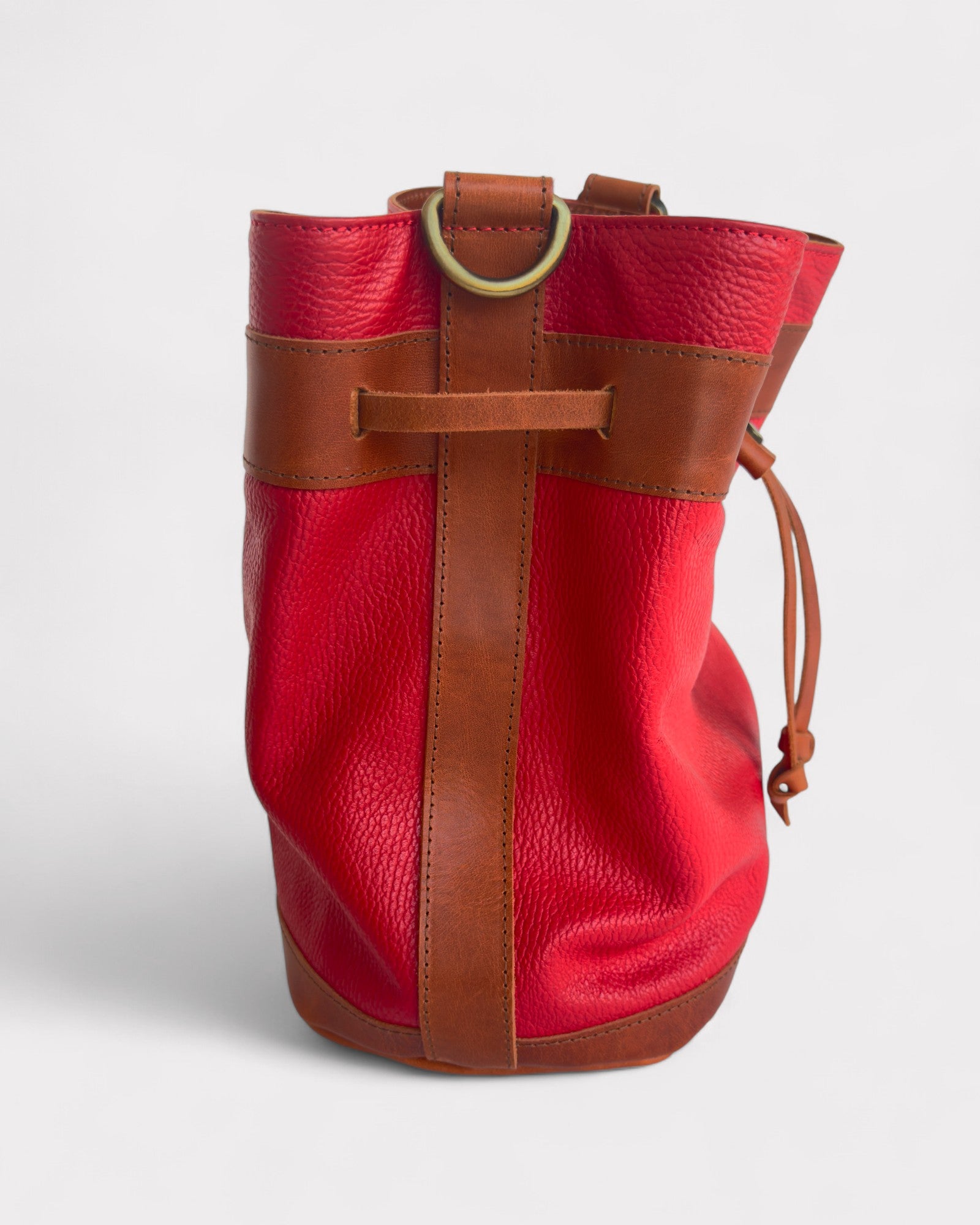 Red leather bucket bag with brown accents on a white background