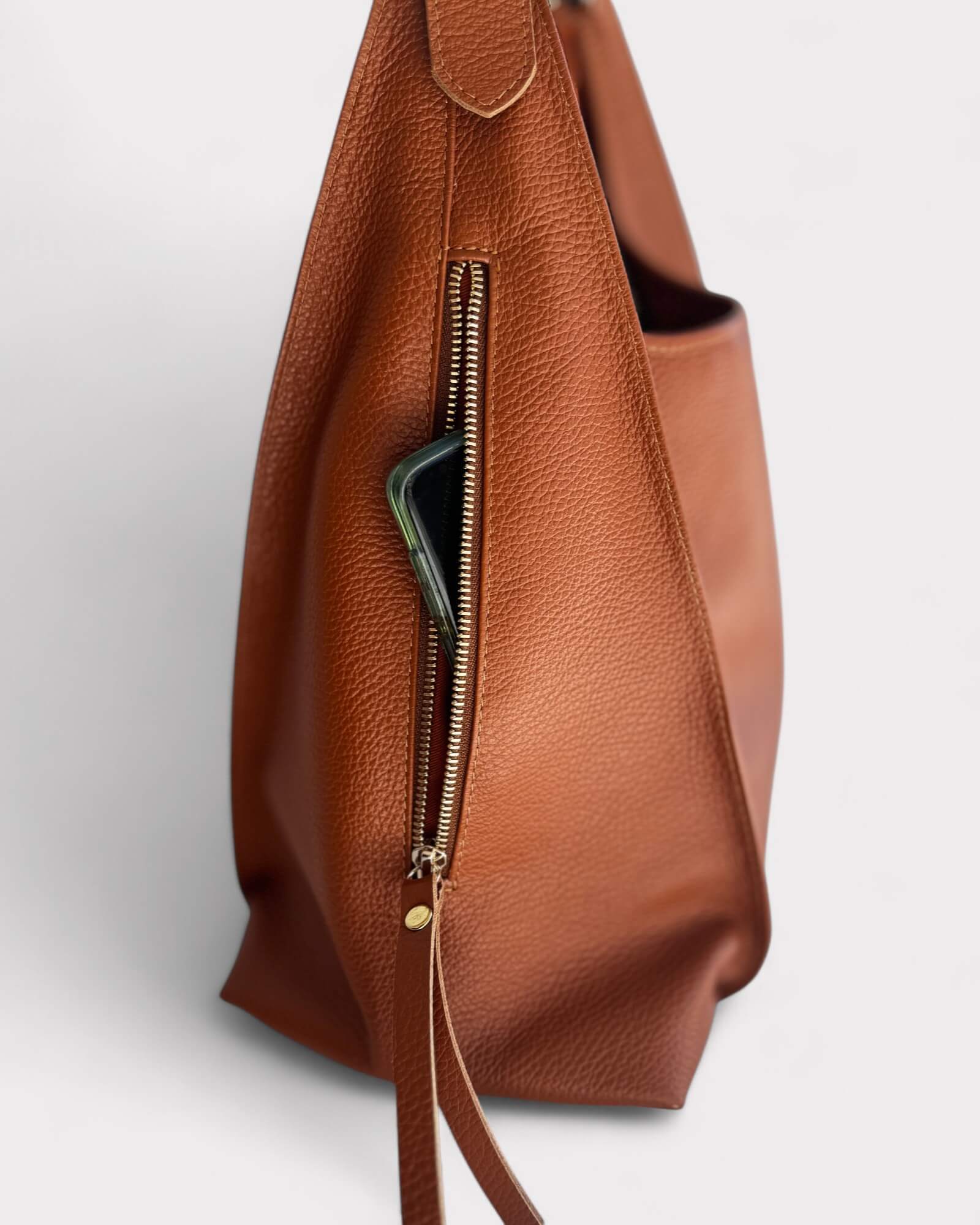 Tan leather bag with a zipper on a white background
