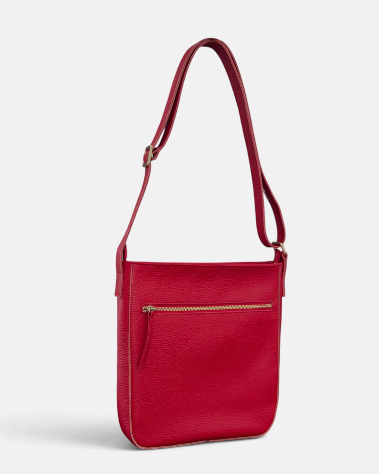 A red textured leather crossbody bag with a front zippered pocket and a gold-tone zipper, shown on a light gray background.