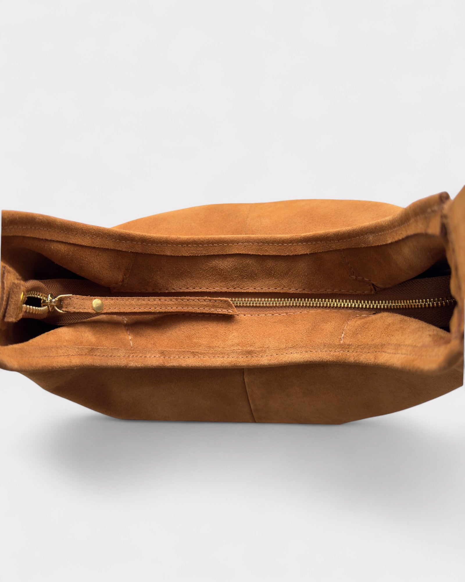 Tan leather bag with a gold zipper on a light gray background
