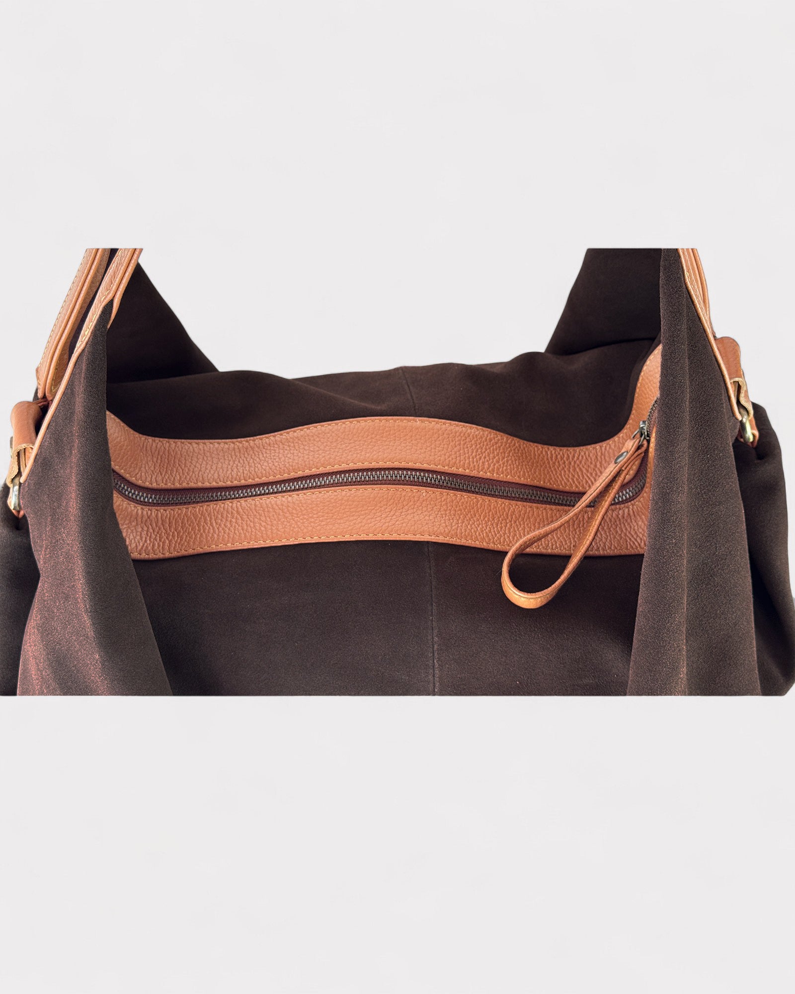 Brown leather handbag with a visible zipper on a light gray background