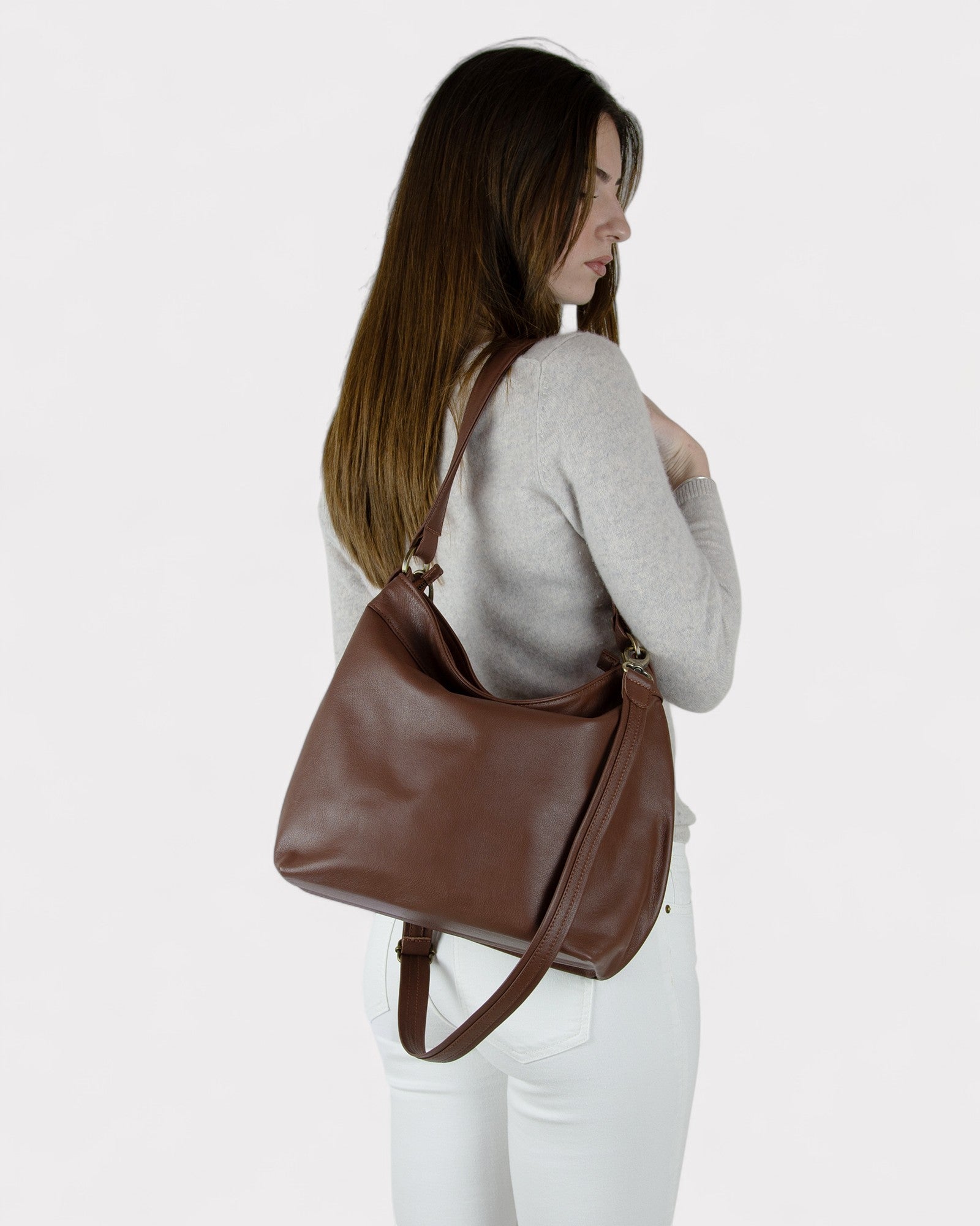 Woman carrying a brown leather bag on a plain background
