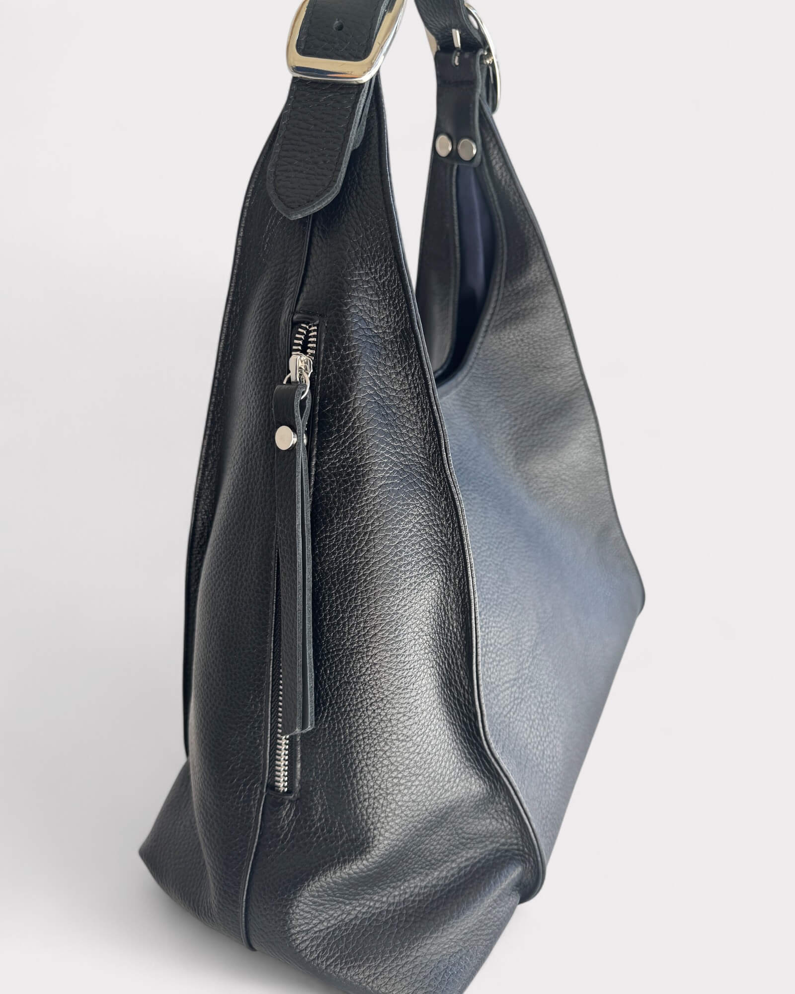 Black leather handbag with a strap on a light gray background