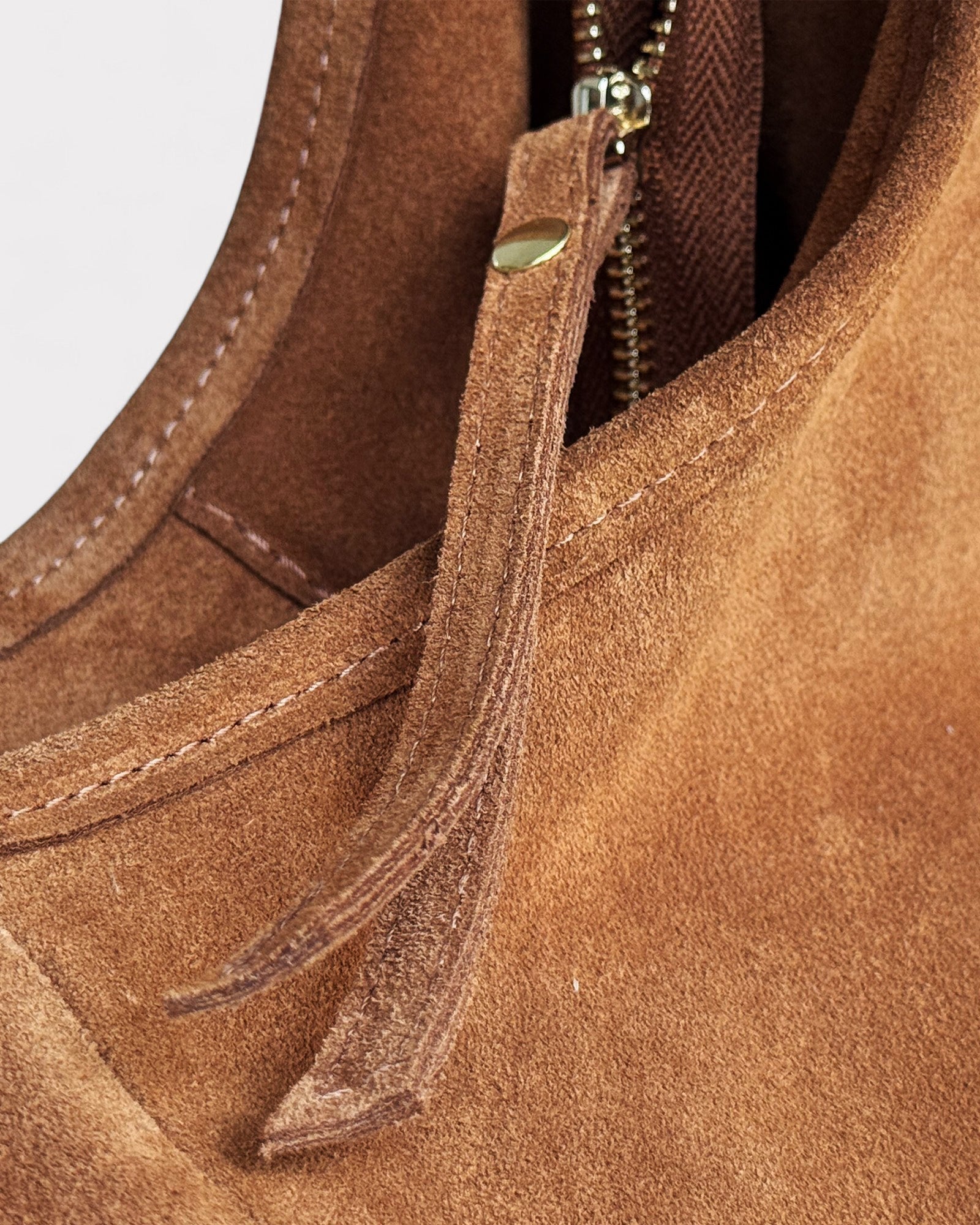 Close-up of a tan suede handbag with a zipper